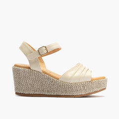 Sandalia de rafia con cuña alta, piel napa o laminada y pulsera Crema